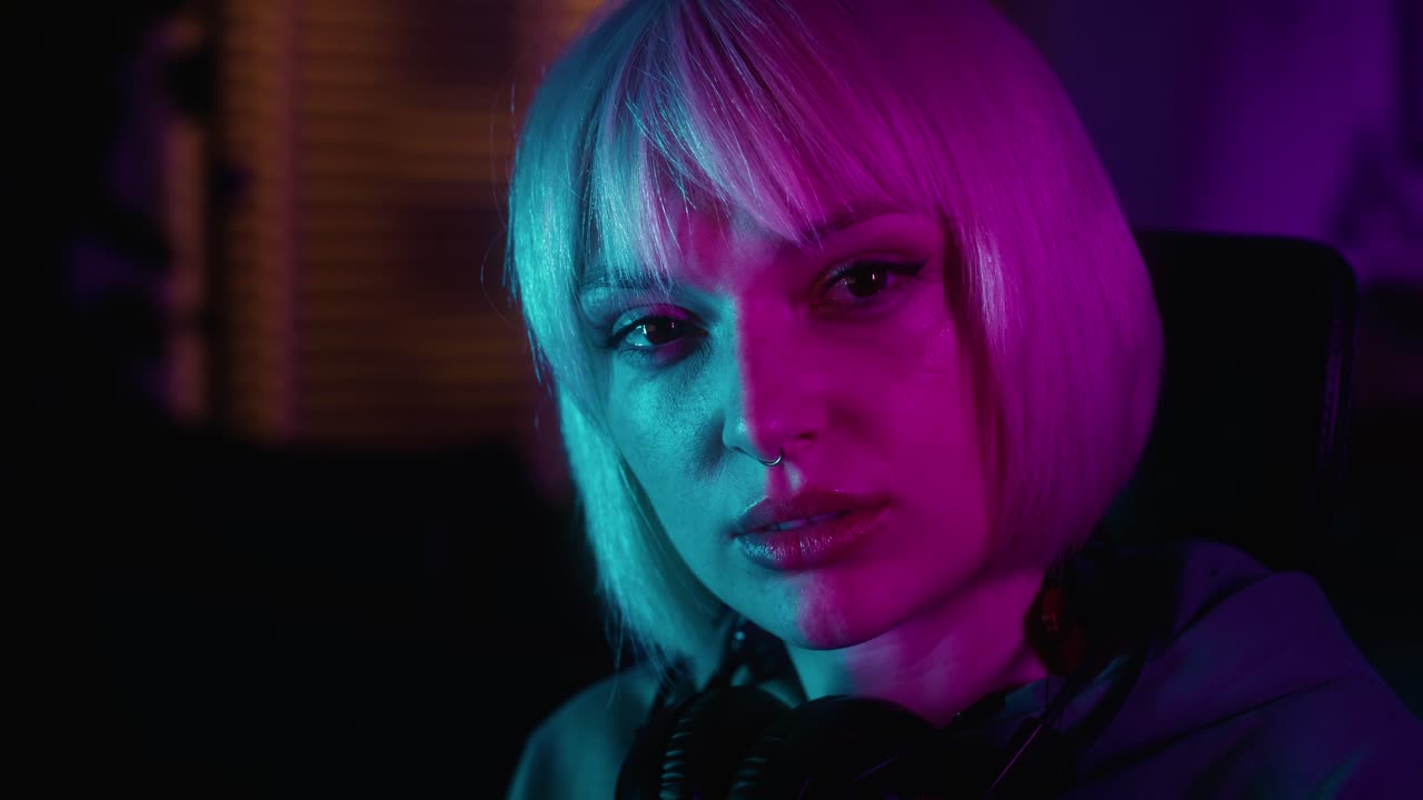 심각한 젊은 백인 여성은 데스크 ⁇  pc에서 밤에 게임을 하는 동안 휴식을 취하는 동안 휴대 전화를 탐색