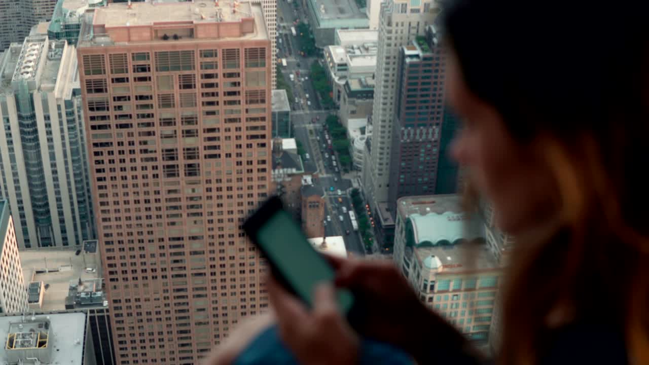 una joven atractiva usando un teléfono inteligente. una mujer de pie cerca de la ventana en un rascacielos en chicago, estados unidos.