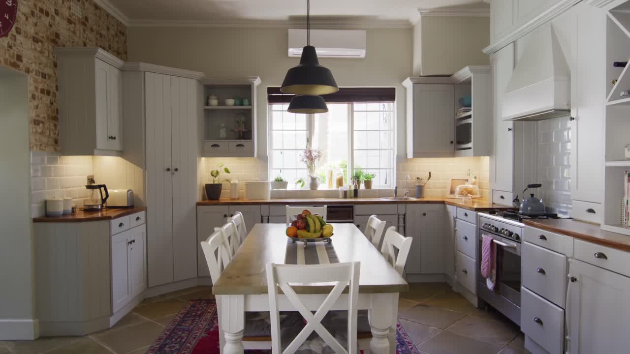 Vista geral do interior da cozinha com armários, bancada e mesa