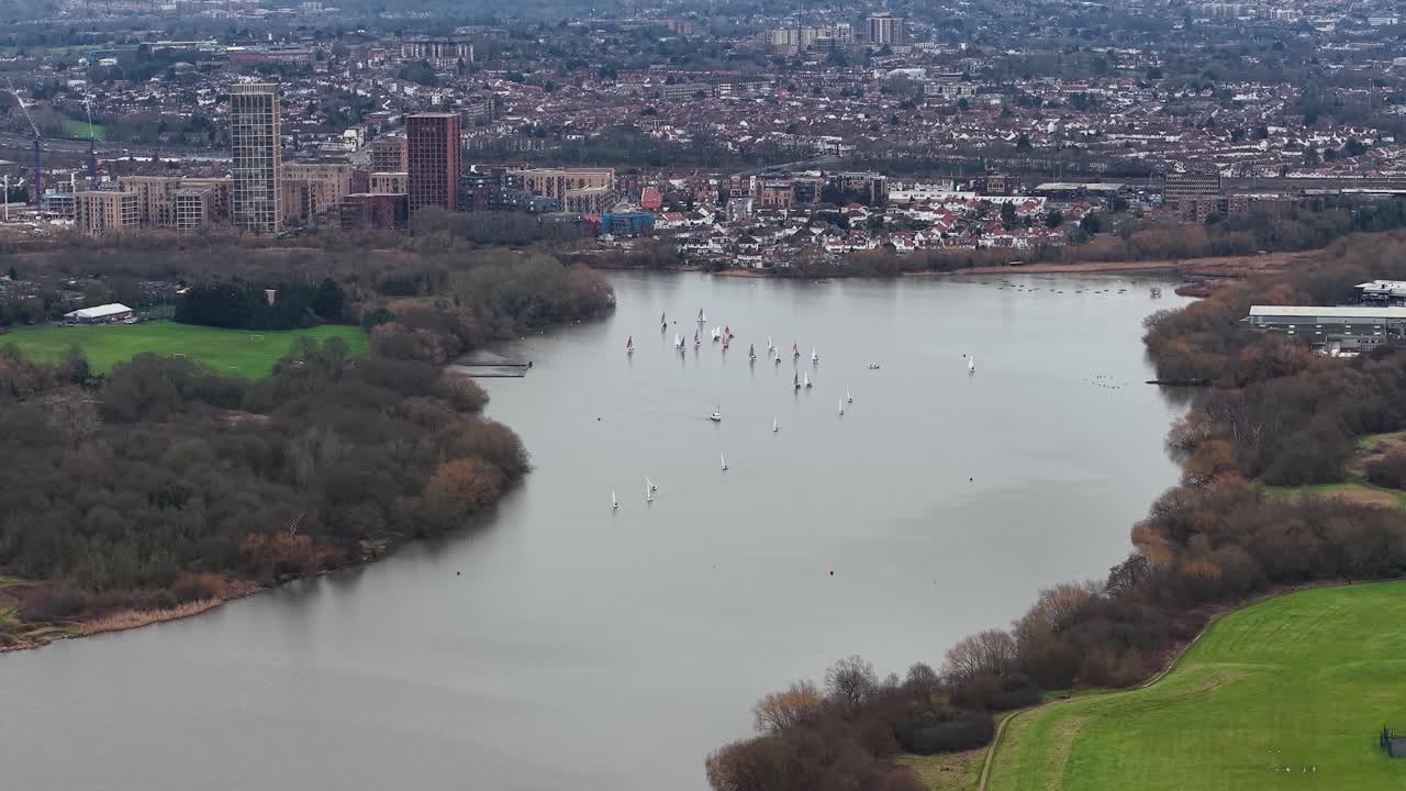 Aerial view descending over Brent reservoir lake overlooking Wembley to London city skyline