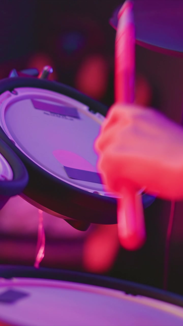 Bacchetta rossa luminosa che colpisce ripetutamente un pad elettronico in primo piano, con luci di scena rosa e viola vivaci che creano effetti visivi dinamici in tutta la scena