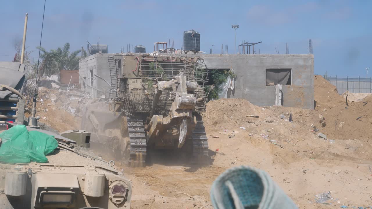 las excavadoras blindadas idf caterpillar d9 se mueven lentamente por las calles de la ciudad destruida durante la guerra de israel-hamas.