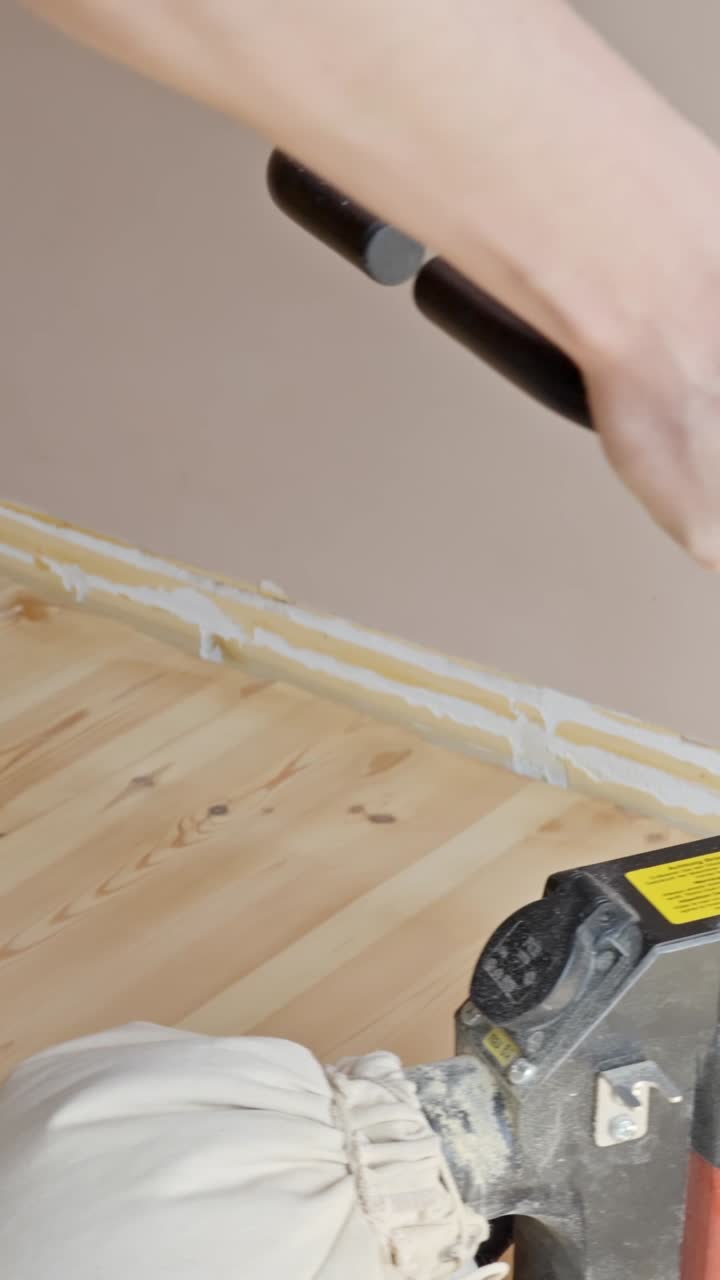 Power sander removing surface layer near floor trim in home improvement, back and forth in smooth consistent motions