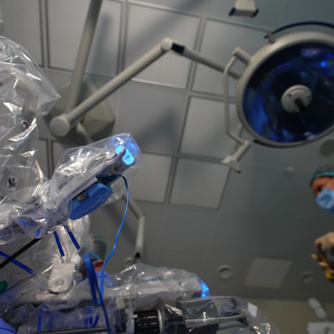 Manipulator active arms of Da Vinci robot moving covered in plastic. Female doctor brings a syringe and gives it to a male colleague. Low angle view