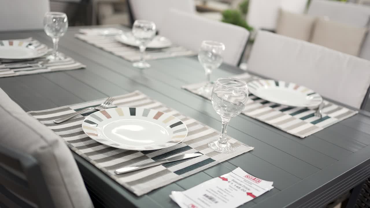 An inviting outdoor dining table is carefully arranged with stylish plates and sparkling glasses. The cozy atmosphere sets the perfect scene for a family gathering