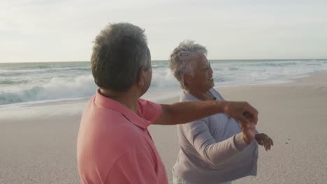 Glückliches-Hispanisches-Seniorenpaar,-Das-Bei-Sonnenuntergang-Am-Strand-Tanzt