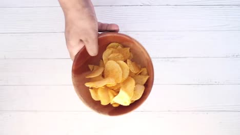 hand holding a bowl of potato chips