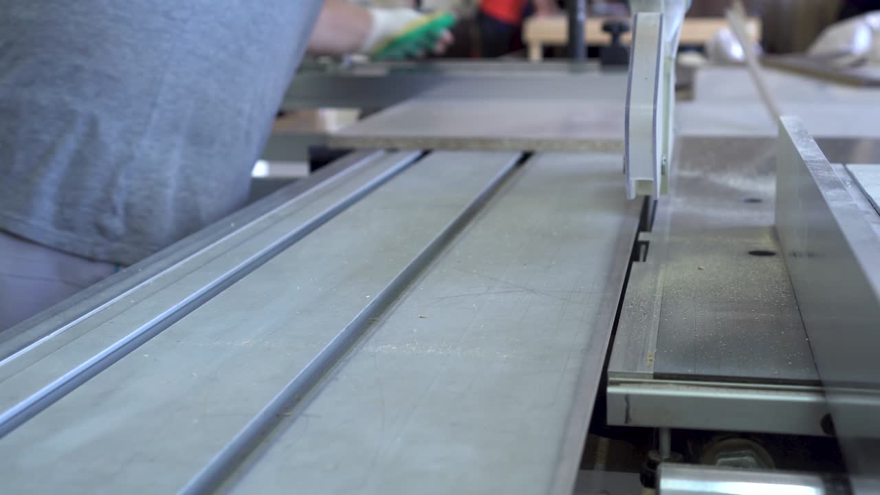 한 남자가 가구 제조 공장에서 원형 도자기로 나무 부품을 고 있습니다.