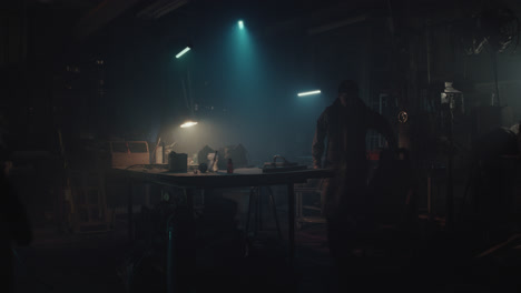 a bombmaker assembles a bomb in his workshop at night