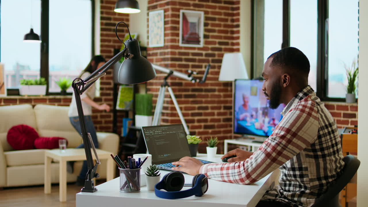 African american software developer works on programming code on a laptop