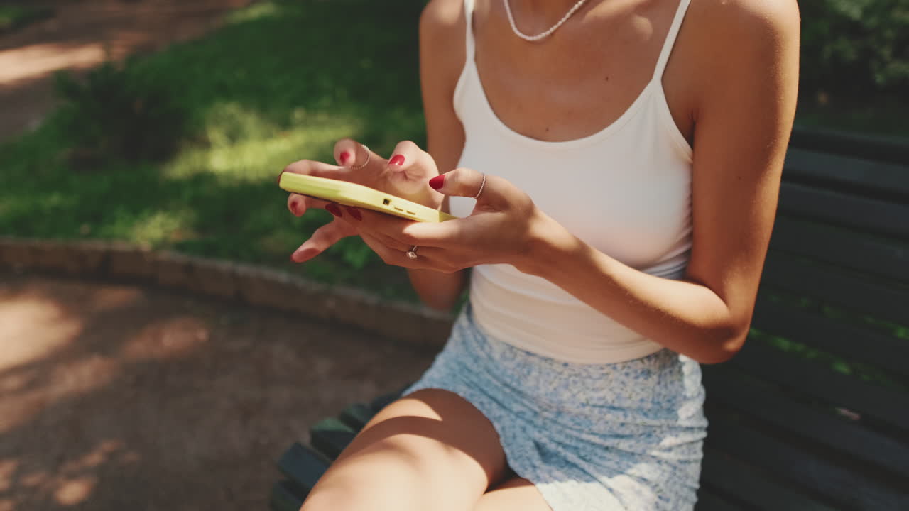Woman using a phone while sitting on a bench in a park