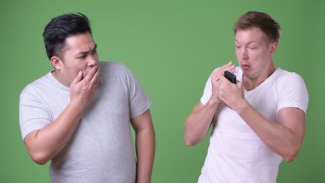두 명의 젊은 다민족 잘생긴 남자들이 녹색 배경에 함께 있습니다.