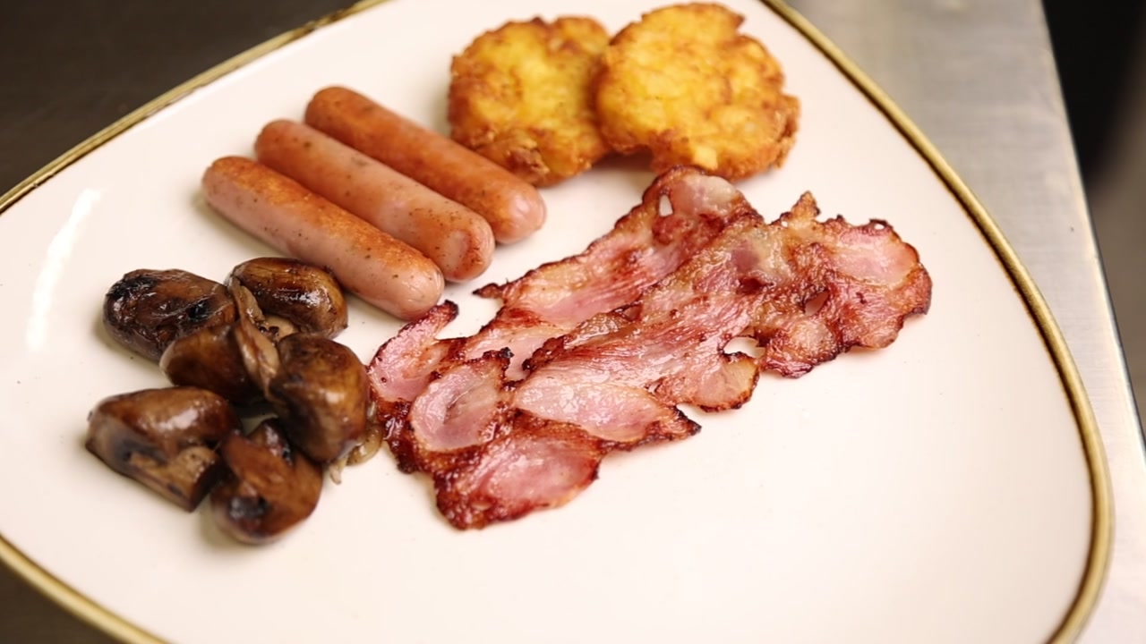 Abbondante colazione con pancetta croccante, salsicce, hash brown e funghi