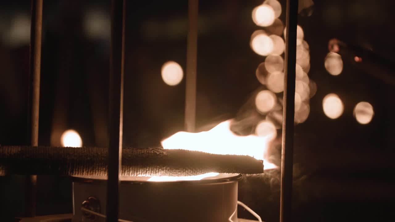 Close-up footage of a flammable stick igniting in slow motion, set against a dark, atmospheric night backdrop
