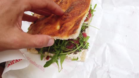 close-up of italian focaccia sandwich: herb‑topped flatbread with jam and green leaves