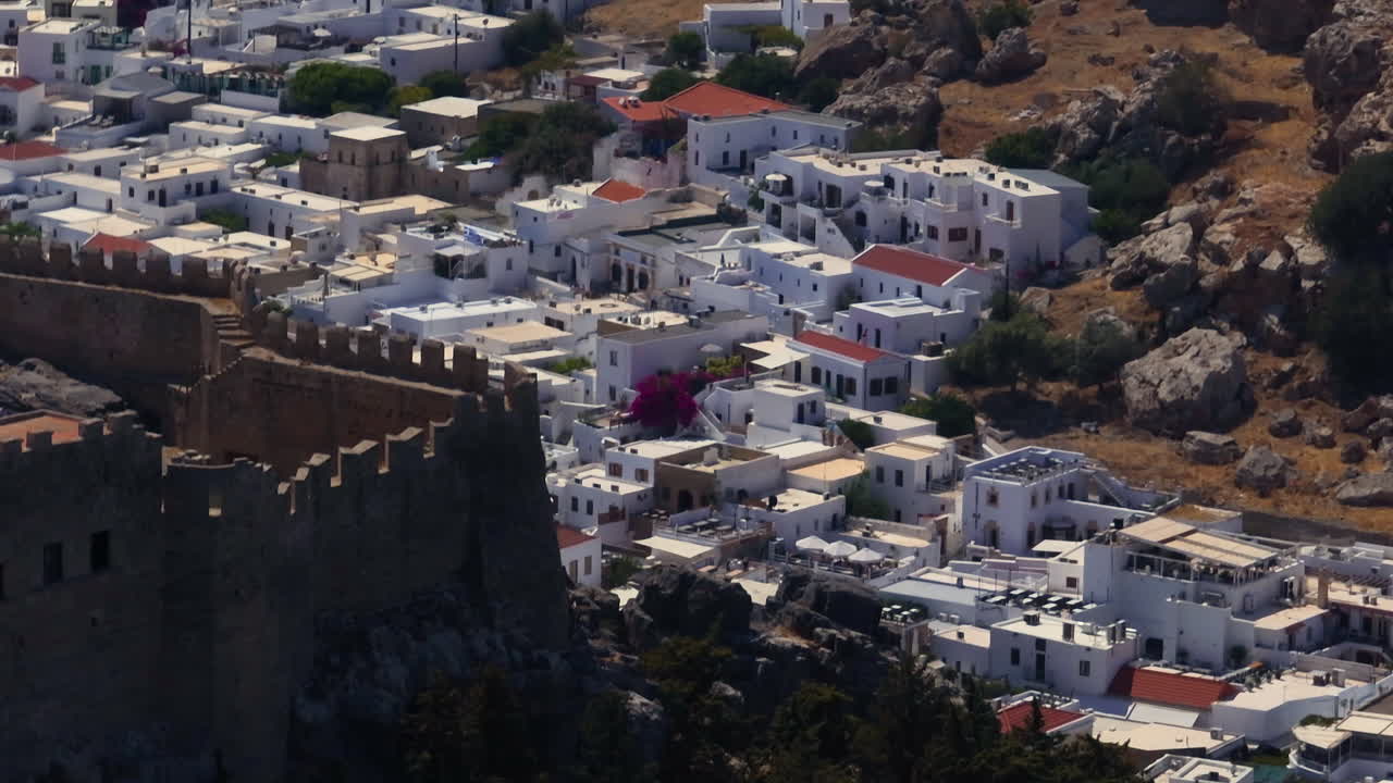 Telephoto drone shot the acropolis wall and the Lindos townscape in sunny Rhodes