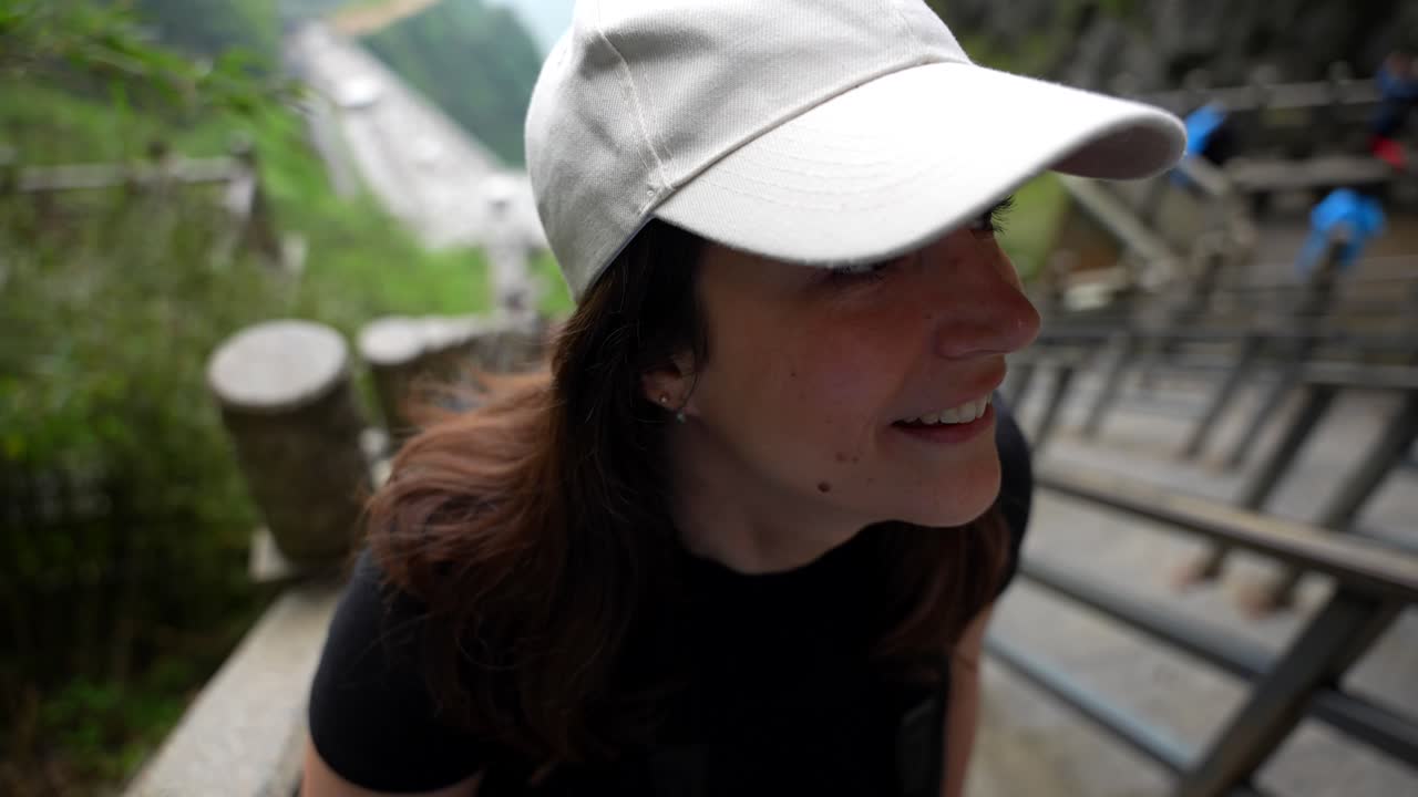 웃는 여자가 중국 장지아지 동굴에 도착한 후 천안산의 가파른 계단을 즐기고 있습니다.