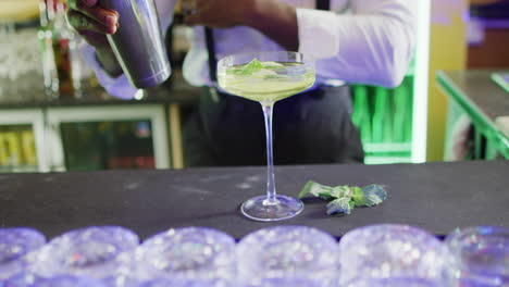 video of midsection of african american barman preparing green cocktail at the bar