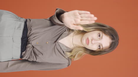 video vertical de una mujer joven haciendo una señal de alto para la cámara.