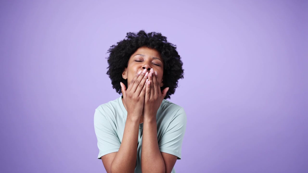 Donna afroamericana felice che manda un bacio su sfondo viola
