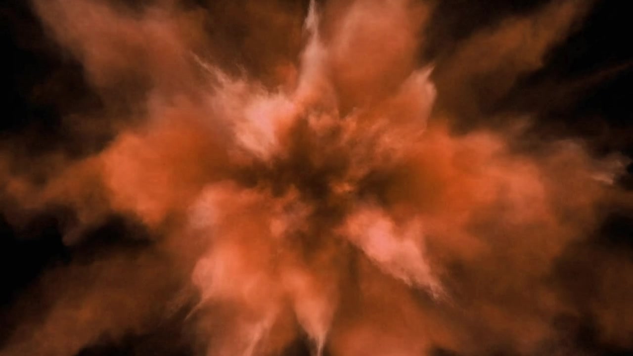 Orange Powder Explosion Against Black Background