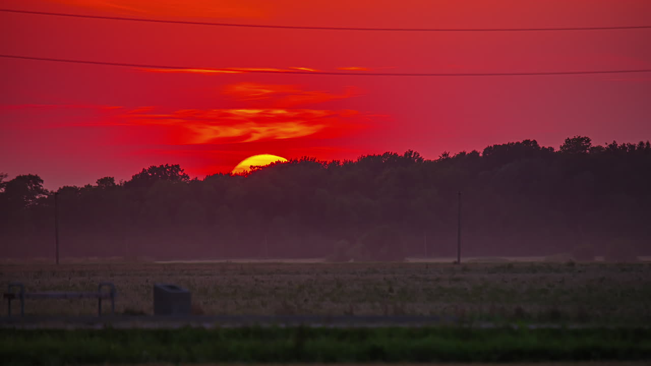 황금 태양이 불타는 해가 지는 하늘에 어두운  ⁇  위에 지고 있습니다.