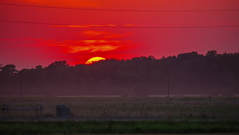 el sol dorado poniéndose sobre el campo oscuro contra el cielo ardiente del atardecer