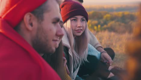 girl spends time with friends at burning bonfire in evening