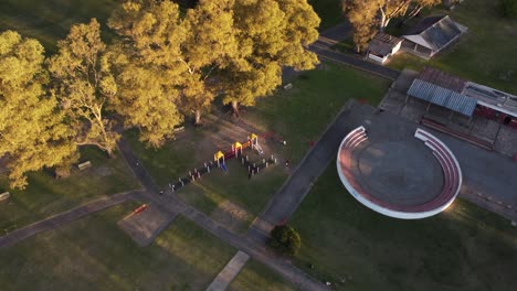 aerial top down of kids playing at playground in sarmiento park during sunset light - buenos aires,south america