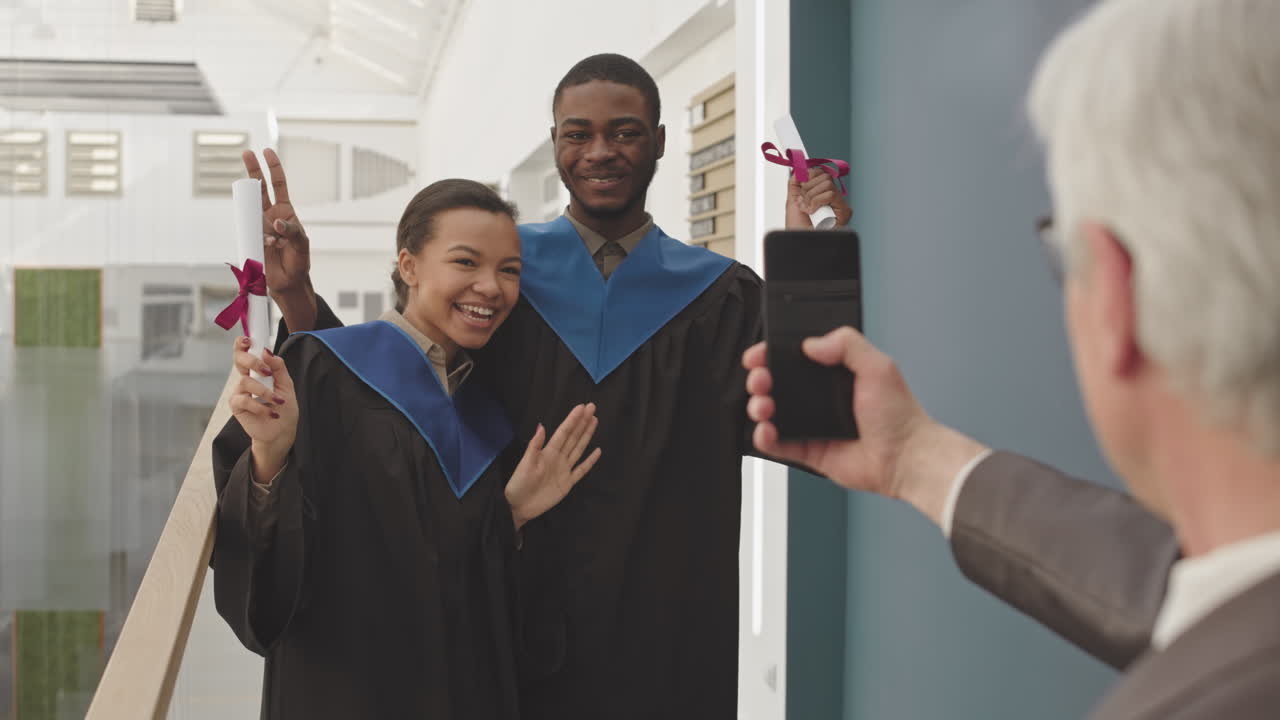 Aged Man Making Photo of Two African-American Graduates