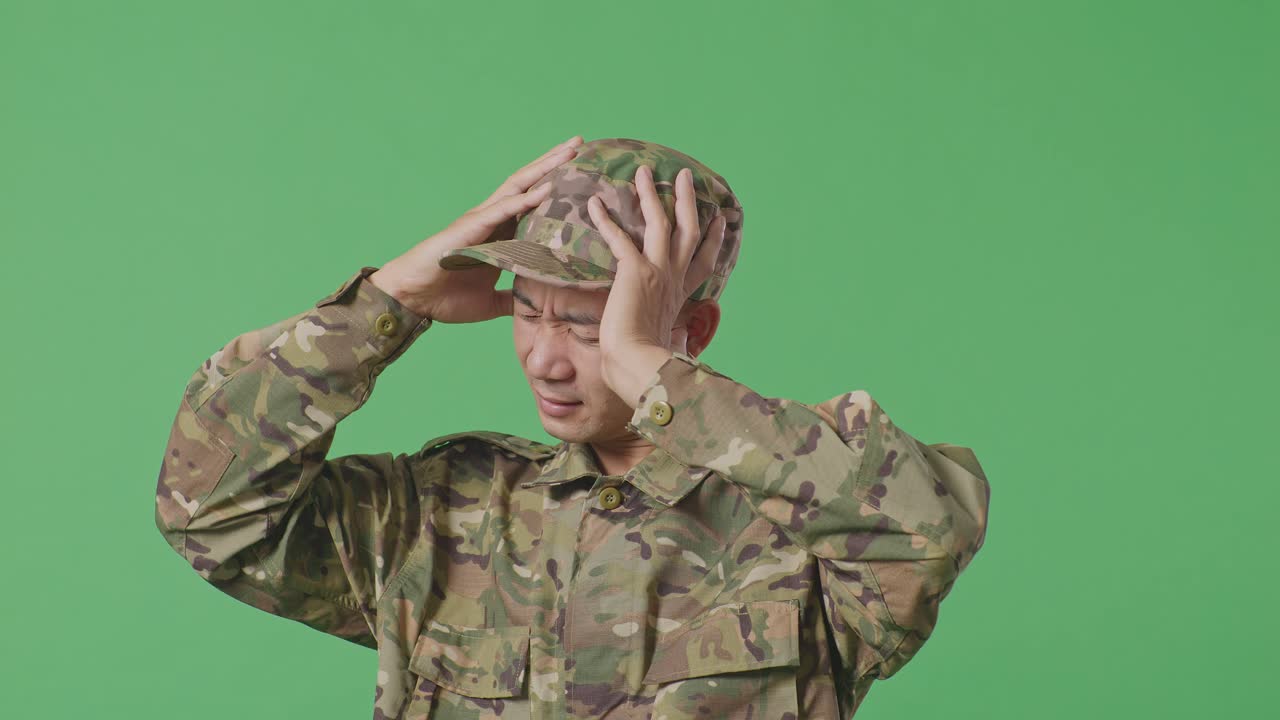 Close Up Of Asian Man Soldier Having A Headache While Standing In The Green Screen Background Studio