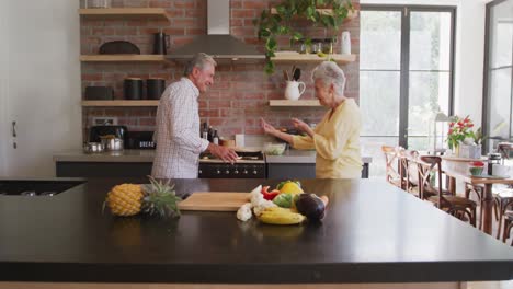 pareja caucásica mayor bailando y sonriendo en la cocina