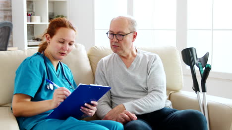 asistente de atención médica femenina tomando notas sobre la salud de un anciano en un acogedor hogar de ancianos