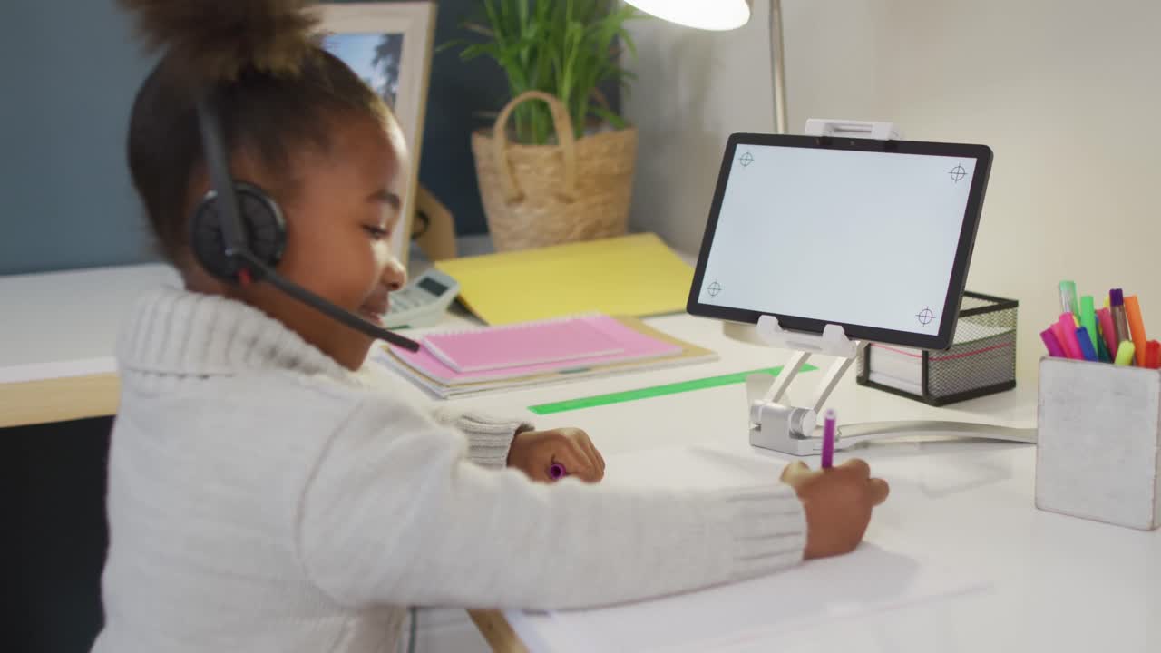 African american girl sitting at table and having video call