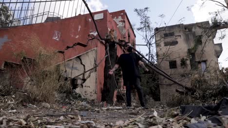 beirut lebanon explosion aftermath: young caucasian man wearing face mask walks in unbelief in debris by downtown buildings destroyed by blast, covid-19 pandemic, low vantage static