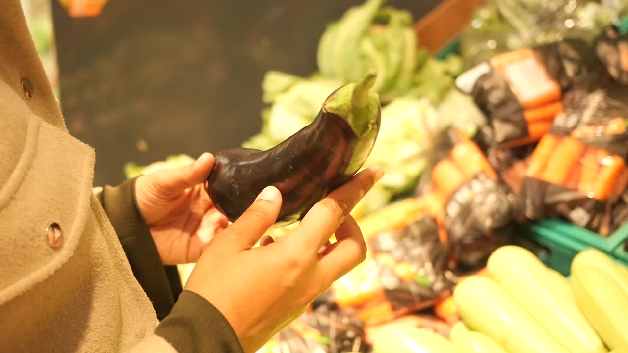 Person holding an eggplant in a grocery store