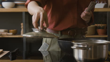 woman cooking noodles in kitchen