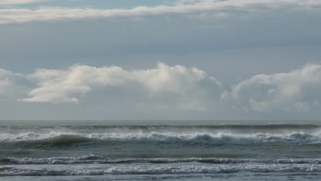 Strong-off-shore-wind-creates-sea-spray-on-incoming-waves-in-winter---Sumner-Beach,-Christchurch,-New-Zealand