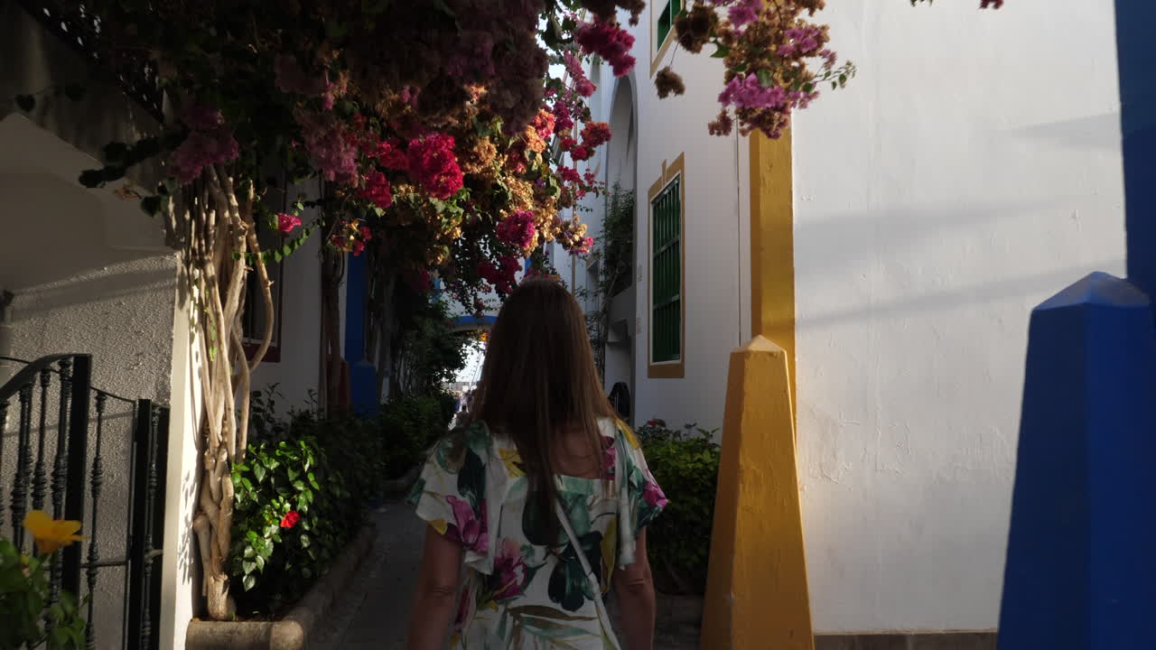 Vrouw loopt door de straten van Puerto de Mogan tijdens zonsondergang.