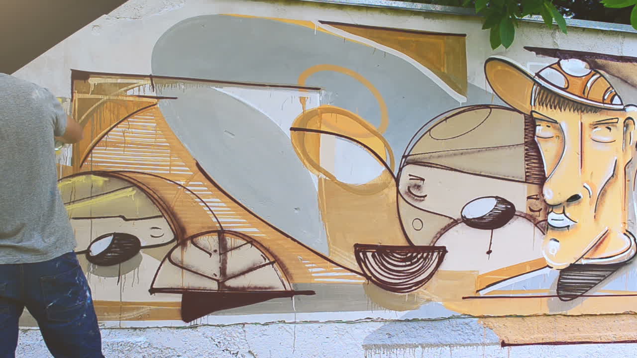 Kunstneren tegner graffiti på et hegn. Abstrakt tegning