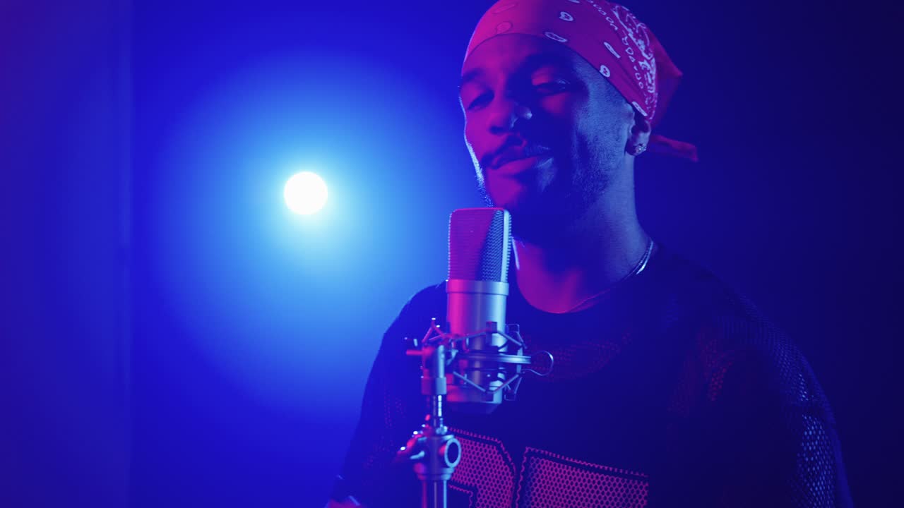 Man singing into a microphone with a bandana