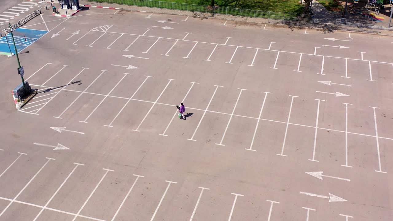 Aerial View of a Person Walking in a Vast Empty Parking Lot