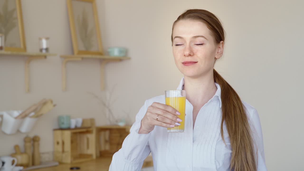 Woman Drinking Orange Juice in Kitchen