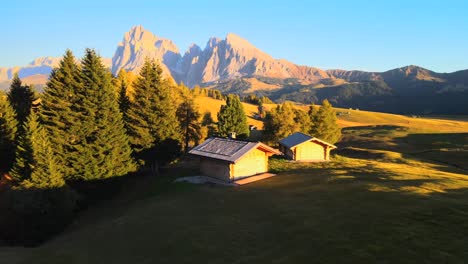 Mountains,-forest-and-grass-fields-with-wooden-cabins-filmed-at-Alpe-di-Siusi-inEuropean-Alps,-Italian-Dolomites-filmed-in-vibrant-colors-at-sunset