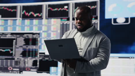 black professional administrator examining digital dashboard with finance graphs