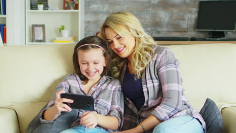 Young-mother-and-her-daughter-relaxing-on-the-couch