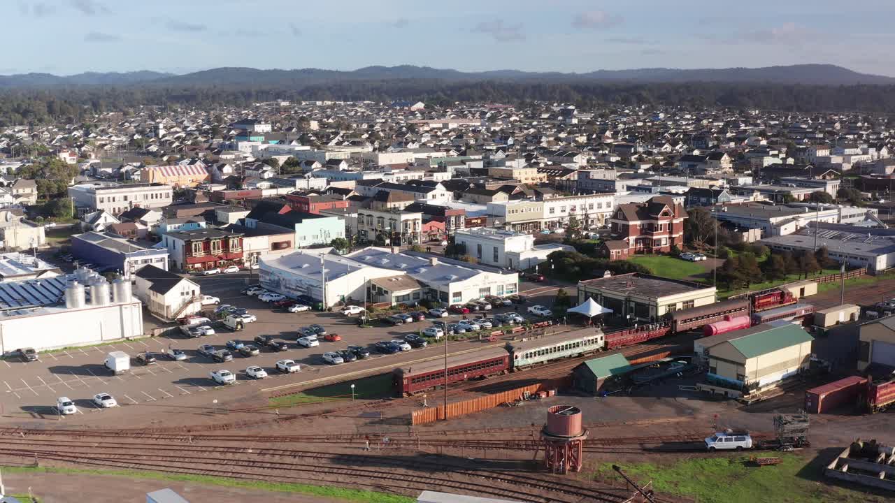 Aerial descending close-up shot of the famous Skunk Train arriving at the downtown depot in Fort Bragg, California. 4K