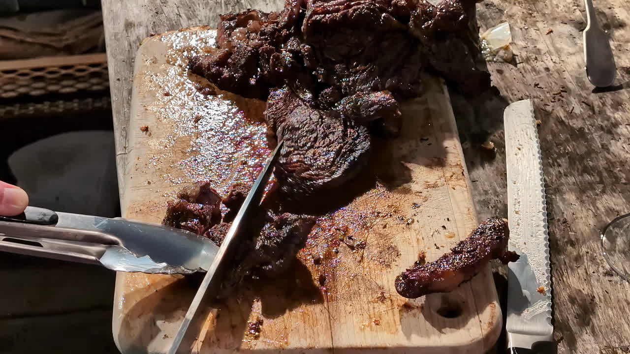 carne roja cortada en una tabla de cortar de madera durante una barbacoa al aire libre
