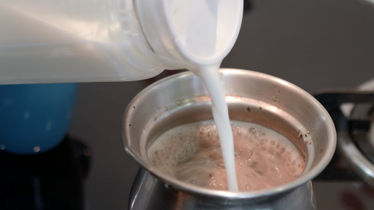 Versando il latte nel tè Masala Chai bollente.