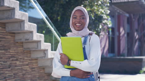 young muslim woman with books on campus